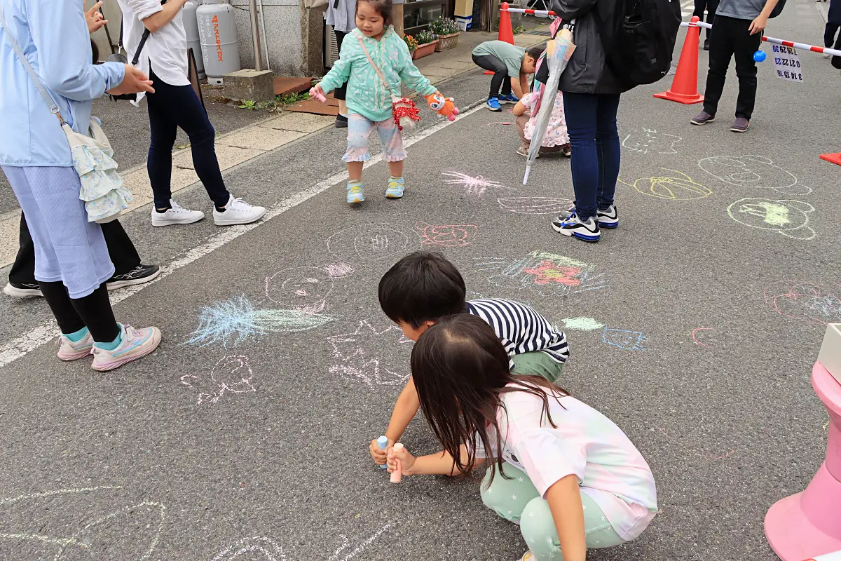 チョークを使って道路にお絵描きする子供たち = 2024年6月2日 十日町通り