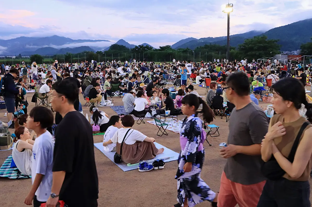 花火観賞スペースにシートを広げて打ち上げを待つ人たち = 2024年7月27日 三友エンジニア体育文化センター